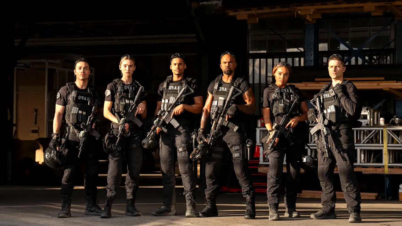 O elenco da série S.W.A.T. Exiles vestido com uniformes táticos pretos, coletes à prova de balas e armamento pesado em um cenário de galpão iluminado pelo sol