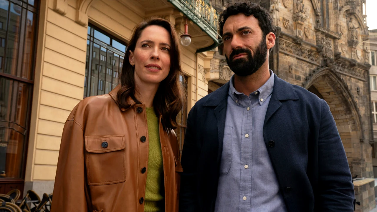 Os atores Morgan Spector e Rebecca Hall caracterizados como Robert Langdon e Katherine Solomon caminhando por uma rua de Praga durante as filmagens da série The Secret of Secrets.