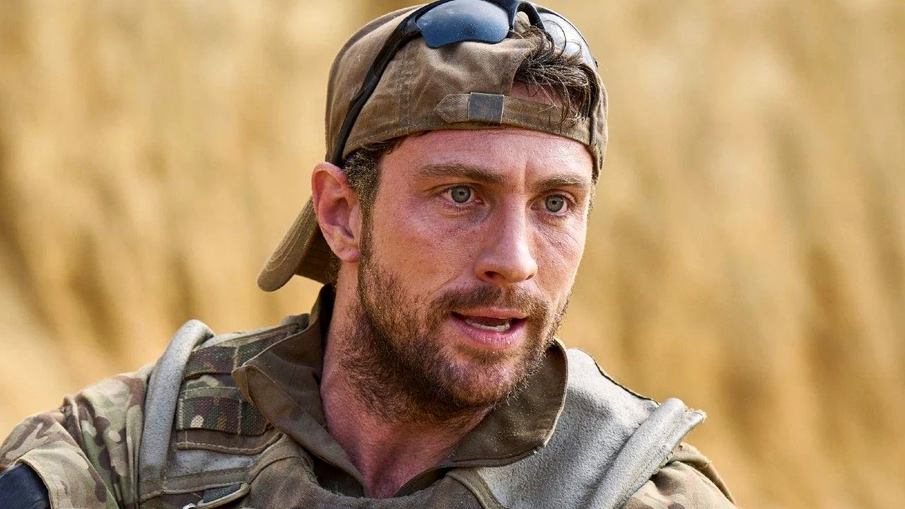 O ator Aaron Taylor-Johnson vestido com uniforme tático militar, colete e boné em uma cena sob a luz do sol.